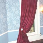 A burgundy velvet panel over hand-made silk rose panel, draped over the customer's antique vaseline glass holdbacks.